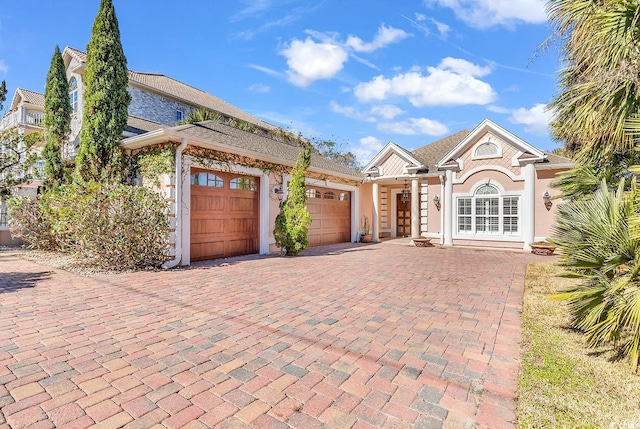 view of front of property with decorative driveway, a garage, and stucco siding