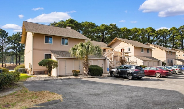 multi unit property with central AC, stairway, a residential view, stucco siding, and a chimney