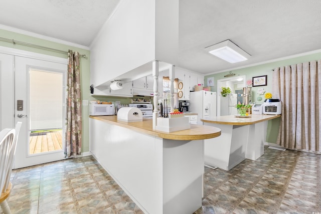 kitchen featuring white appliances, ornamental molding, a peninsula, light countertops, and white cabinetry