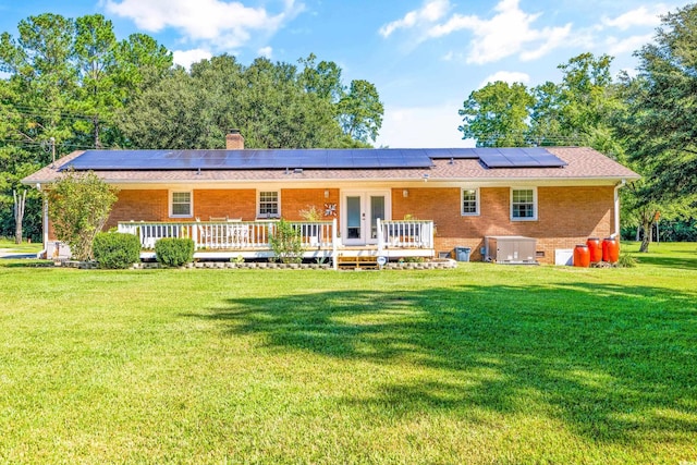 back of house featuring central air condition unit, brick siding, a yard, french doors, and a chimney