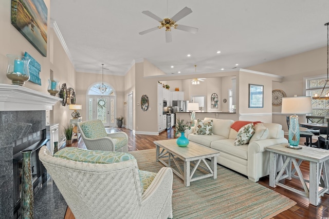 living area with a healthy amount of sunlight, ornamental molding, wood finished floors, and a tile fireplace