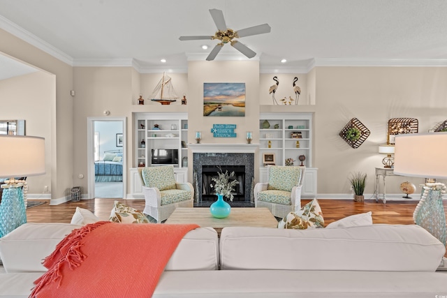 living room with baseboards, a premium fireplace, ornamental molding, wood finished floors, and built in shelves