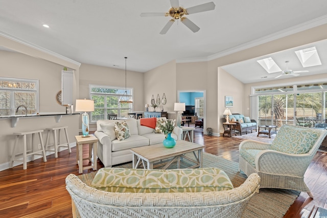 living room featuring a skylight, crown molding, a ceiling fan, wood finished floors, and baseboards