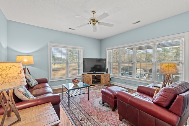 living room featuring baseboards, ceiling fan, visible vents, and wood finished floors