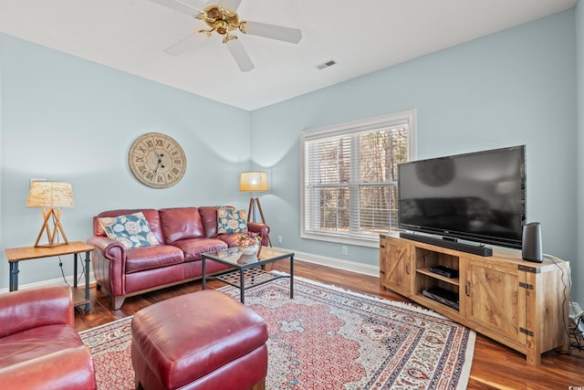 living room featuring a ceiling fan, visible vents, baseboards, and wood finished floors