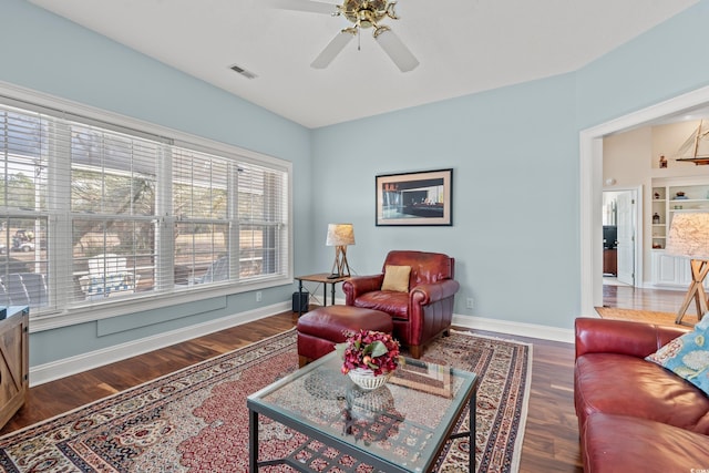 living room featuring visible vents, ceiling fan, baseboards, and wood finished floors