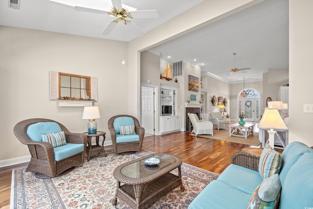 living area featuring a fireplace, ceiling fan, baseboards, and wood finished floors