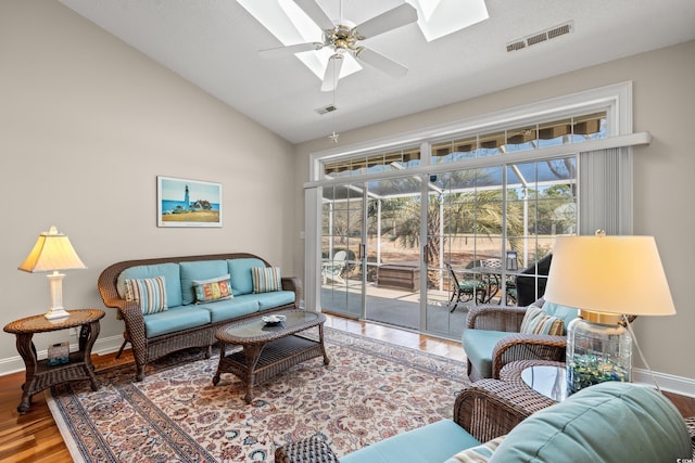 living room with visible vents, a ceiling fan, a sunroom, vaulted ceiling, and wood finished floors