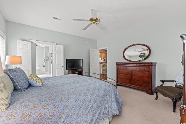 carpeted bedroom featuring ensuite bathroom, visible vents, and a ceiling fan