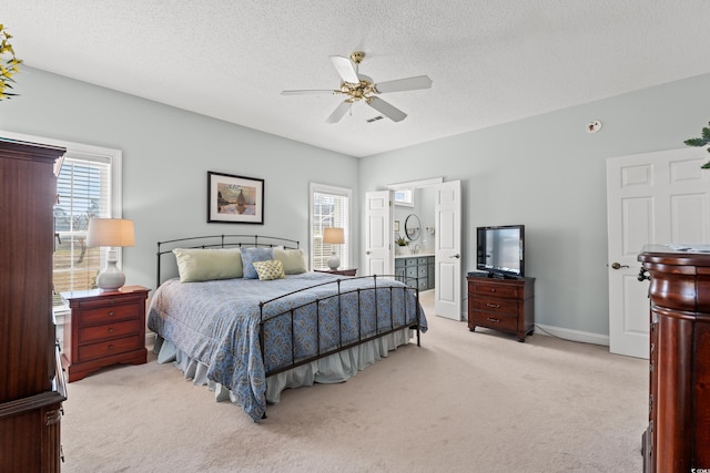 bedroom featuring a textured ceiling, connected bathroom, light colored carpet, a ceiling fan, and baseboards