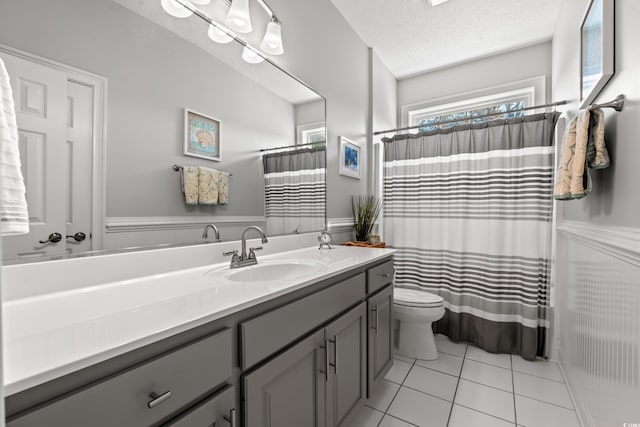 full bathroom featuring wainscoting, a textured ceiling, and toilet