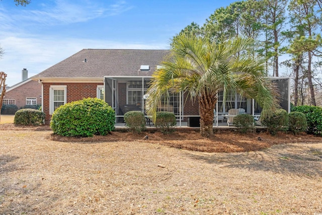 view of front of property with a shingled roof, a sunroom, and brick siding