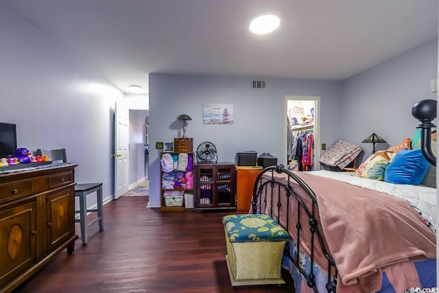 bedroom featuring a walk in closet, wood finished floors, visible vents, and baseboards