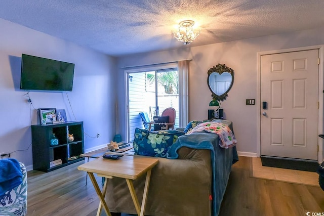 living room featuring a textured ceiling, baseboards, and wood finished floors