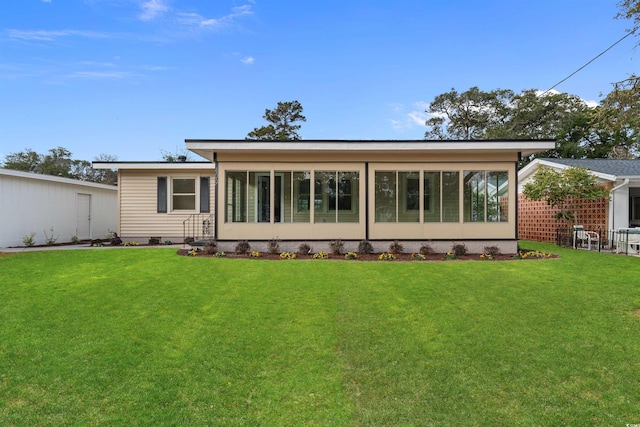 rear view of house with a lawn and a sunroom