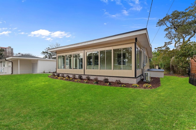 back of property featuring a sunroom and a lawn