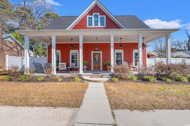 bungalow-style house featuring a shingled roof, covered porch, ceiling fan, and fence