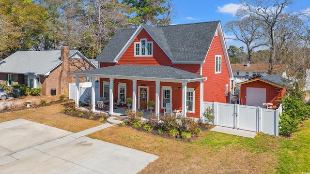 view of front of house featuring roof with shingles, covered porch, a gate, fence, and a front lawn