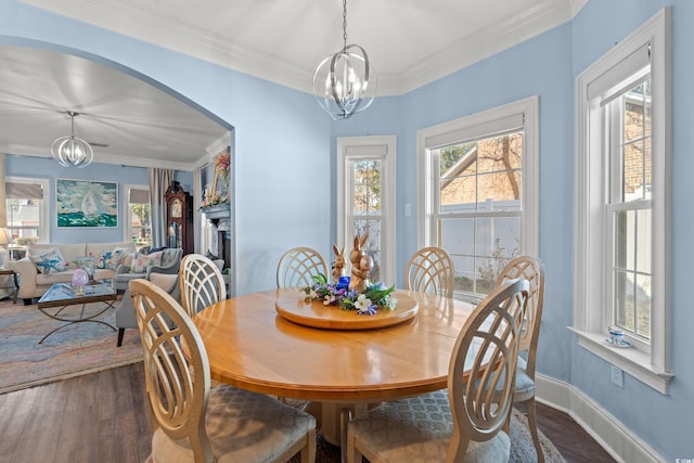 dining room with arched walkways, a chandelier, dark wood finished floors, and crown molding