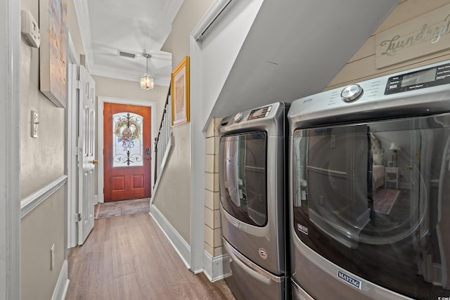 clothes washing area with visible vents, ornamental molding, separate washer and dryer, and wood finished floors