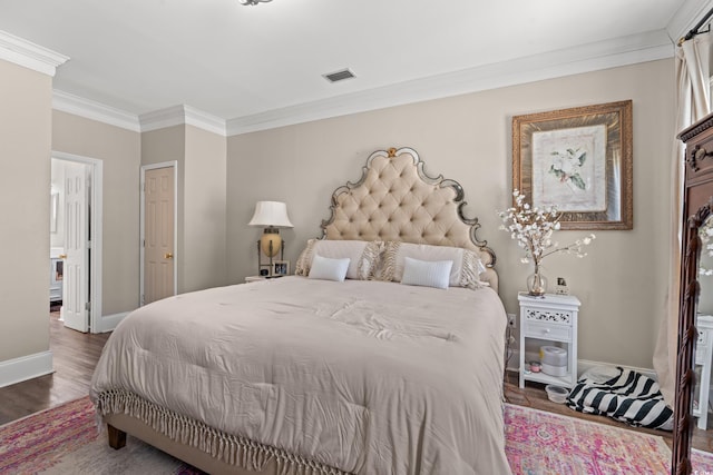 bedroom with visible vents, crown molding, baseboards, and wood finished floors