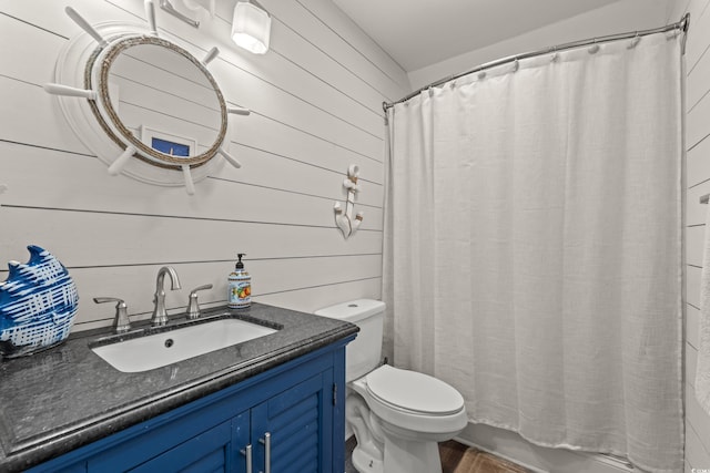 full bath with vanity, toilet, and wooden walls