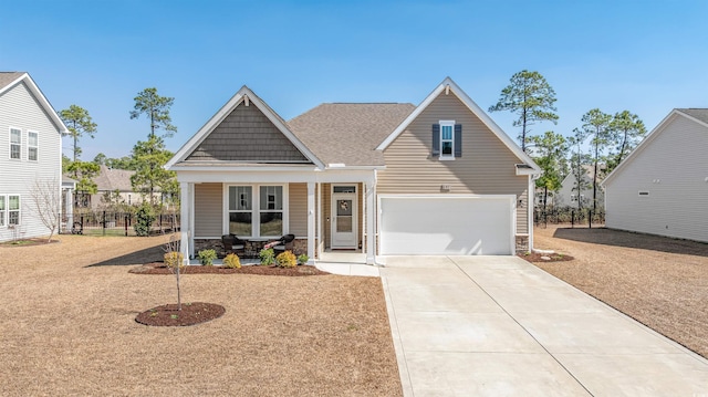 view of front facade with driveway, a garage, stone siding, fence, and a porch