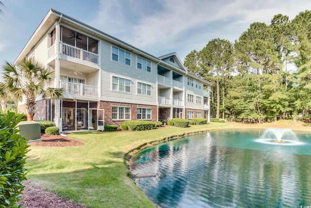 view of pool featuring a lawn, a water view, and a ceiling fan