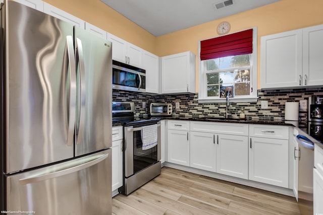 kitchen with stainless steel appliances, visible vents, a sink, and tasteful backsplash