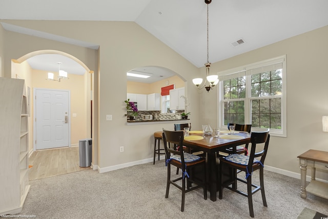 dining space with a notable chandelier, visible vents, light carpet, vaulted ceiling, and baseboards