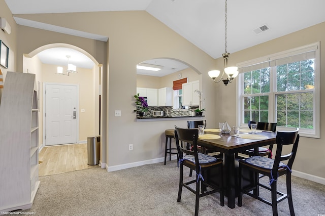 dining room with arched walkways, light colored carpet, visible vents, vaulted ceiling, and an inviting chandelier