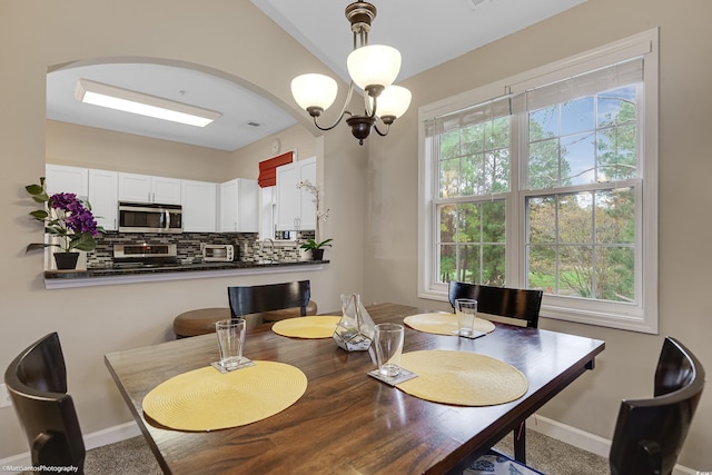 dining area with a chandelier, a toaster, arched walkways, and baseboards