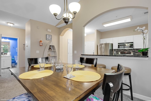 dining space featuring arched walkways, carpet flooring, visible vents, and an inviting chandelier