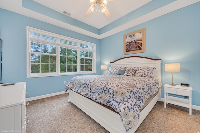 bedroom with carpet, a raised ceiling, visible vents, a ceiling fan, and baseboards