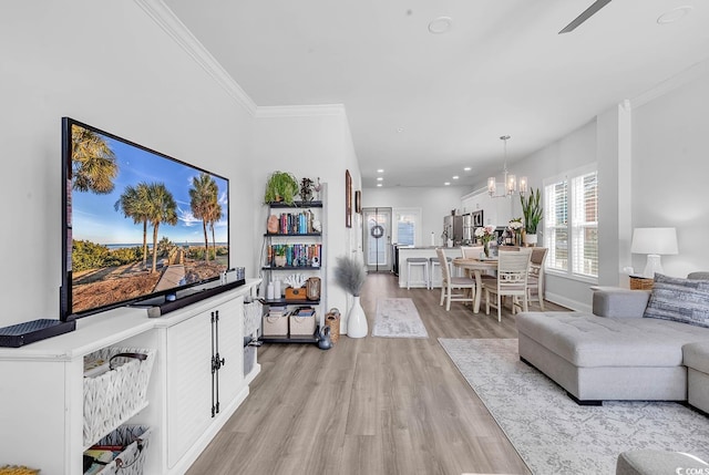 living room featuring baseboards, ornamental molding, light wood-type flooring, a notable chandelier, and recessed lighting