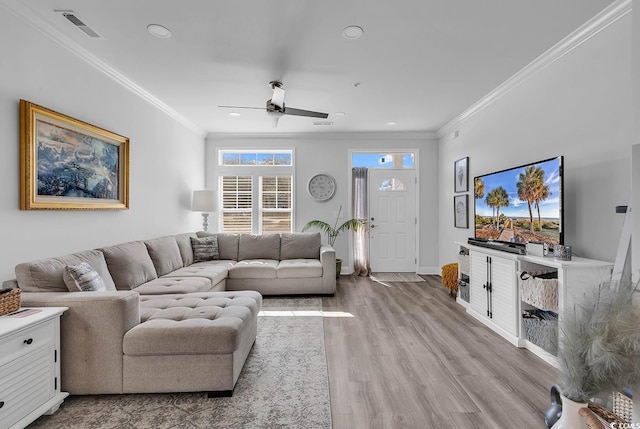 living room with baseboards, visible vents, ceiling fan, crown molding, and light wood-type flooring