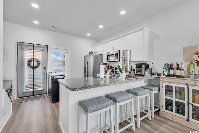 kitchen featuring visible vents, appliances with stainless steel finishes, a peninsula, light wood-style floors, and white cabinetry