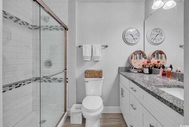 bathroom with double vanity, a stall shower, toilet, and baseboards