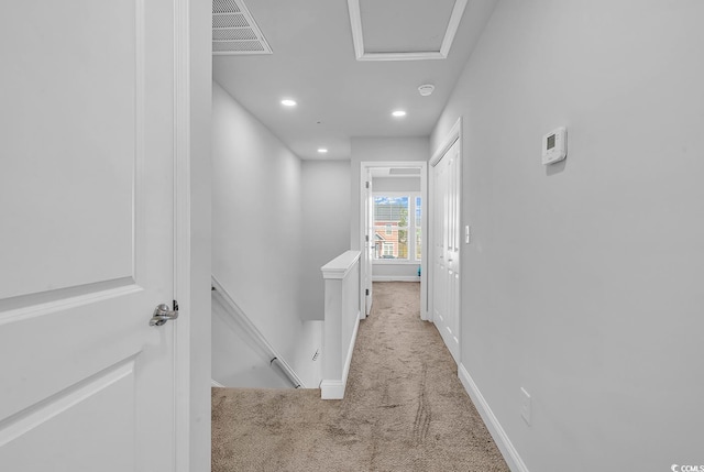 corridor with carpet, visible vents, baseboards, and an upstairs landing