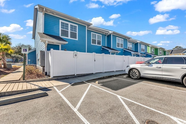 view of front of home with uncovered parking, a residential view, and fence