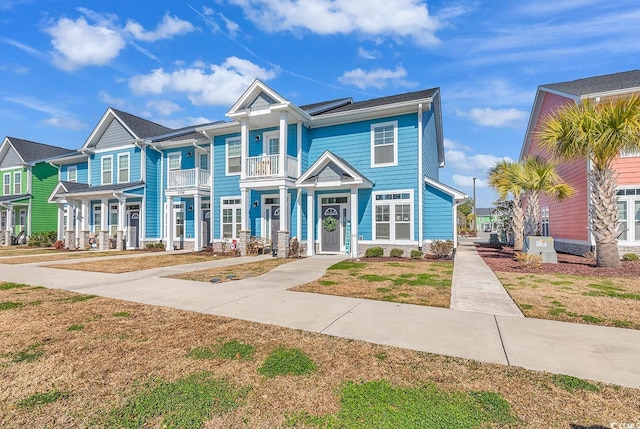 townhome / multi-family property with a residential view, a balcony, and roof mounted solar panels