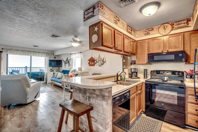 kitchen featuring open floor plan, black appliances, a sink, and visible vents