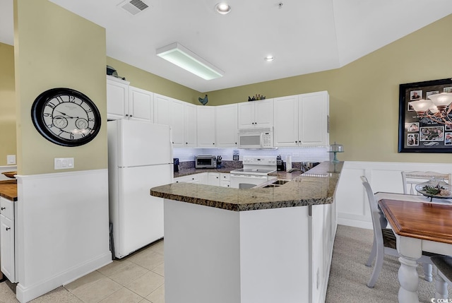 kitchen featuring a peninsula, white appliances, visible vents, white cabinets, and dark countertops