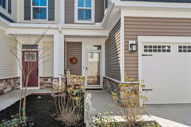 view of exterior entry with stone siding and an attached garage