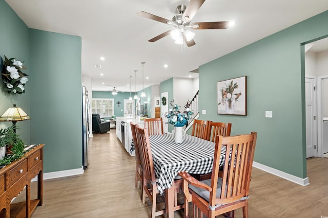 dining room with light wood-type flooring, baseboards, and stairs