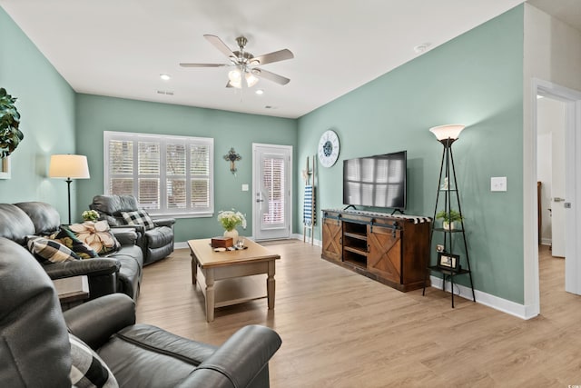 living area with ceiling fan, wood finished floors, visible vents, and baseboards