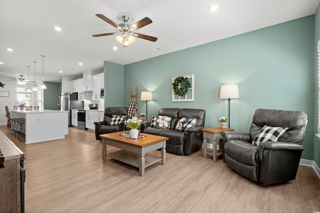 living room featuring baseboards, visible vents, a ceiling fan, light wood-type flooring, and recessed lighting