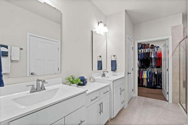 full bath featuring a stall shower, two vanities, a sink, and tile patterned floors