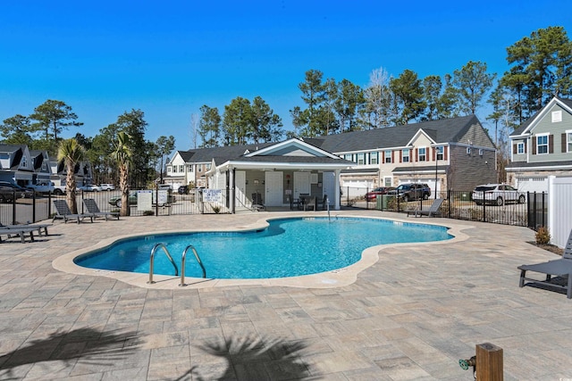 pool featuring a patio area, fence, and a residential view