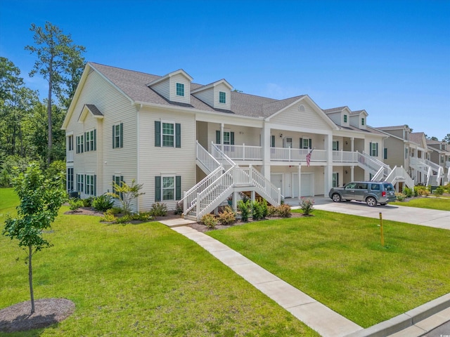 view of front facade with driveway, a garage, stairway, and a front yard